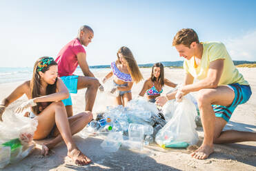 Eine Gruppe freiwilliger Umweltschützer hält nach der Müllsortierung Plastiksäcke in der Hand - Freunde säubern den Strand und sammeln Plastik, um das Leben im Meer zu retten - DMDF04083