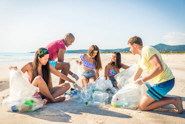 Eine Gruppe freiwilliger Umweltschützer hält nach der Müllsortierung Plastiksäcke in der Hand - Freunde säubern den Strand und sammeln Plastik, um das Leben im Meer zu retten - DMDF04084