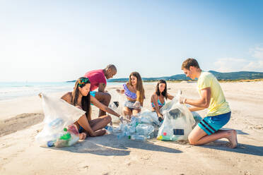 Eine Gruppe freiwilliger Umweltschützer hält nach der Müllsortierung Plastiksäcke in der Hand - Freunde säubern den Strand und sammeln Plastik, um das Leben im Meer zu retten - DMDF04085