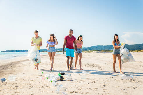 Eine Gruppe freiwilliger Umweltschützer hält nach der Müllsortierung Plastiksäcke in der Hand - Freunde säubern den Strand und sammeln Plastik, um das Leben im Meer zu retten - DMDF04086