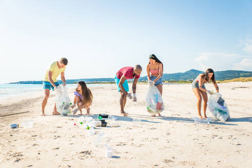 Eine Gruppe freiwilliger Umweltschützer hält nach der Müllsortierung Plastiksäcke in der Hand - Freunde säubern den Strand und sammeln Plastik, um das Leben im Meer zu retten - DMDF04087