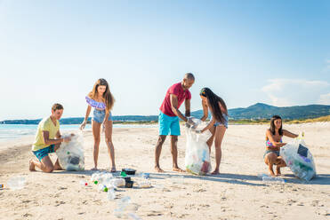 Eine Gruppe freiwilliger Umweltschützer hält nach der Müllsortierung Plastiksäcke in der Hand - Freunde säubern den Strand und sammeln Plastik, um das Leben im Meer zu retten - DMDF04088