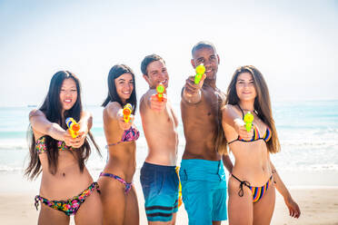 Eine Gruppe von Freunden, die sich am Strand vergnügen - Junge und glückliche Touristen, die sich im Freien treffen und den Sommer genießen - DMDF04131