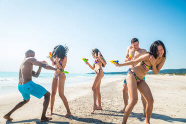 Eine Gruppe von Freunden, die sich am Strand vergnügen - Junge und glückliche Touristen, die sich im Freien treffen und den Sommer genießen - DMDF04136