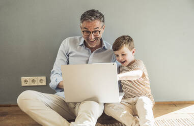 Glücklicher Großvater benutzt den Laptop seines Enkels zu Hause - UUF29978
