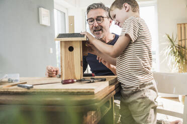 Man making birdhouse with grandson at home - UUF29985
