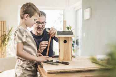 Großvater baut mit seinem Enkel zu Hause ein Vogelhaus aus Holz - UUF29986