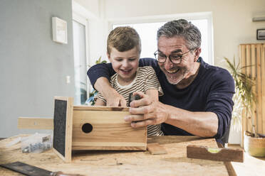 Fröhlicher Großvater und Enkel bauen zu Hause ein Vogelhaus - UUF29995