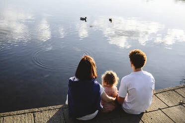 Familie schaut Enten beim Schwimmen im See zu - EYAF02741