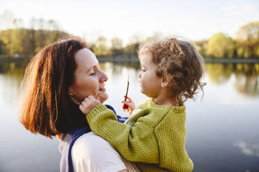 Mutter trägt Tochter am See im Park - EYAF02743