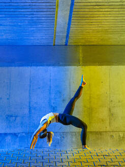 Active woman exercising in front of neon colored wall - STSF03761