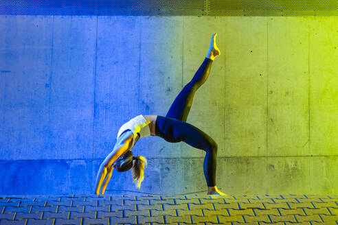 Woman exercising in front of neon colored wall - STSF03762