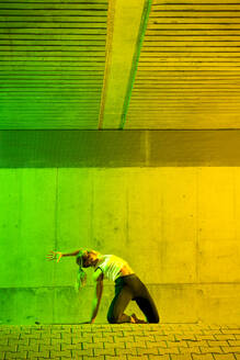 Active woman exercising in front of colored wall - STSF03764