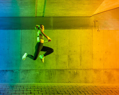 Woman jumping in front of wall - STSF03765