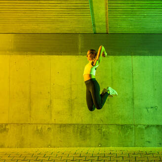 Woman jumping near neon colored wall - STSF03766
