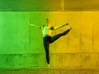 Glückliche Frau beim Yoga vor einer neonfarbenen Wand - STSF03769