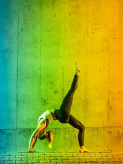 Frau beim Yoga in der Nähe einer neonfarbenen Wand - STSF03772