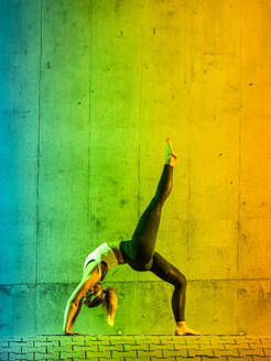 Woman doing yoga near neon colored wall - STSF03772