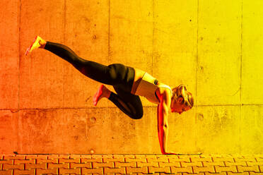 Frau übt Yoga in der Nähe der neonfarbenen Wand - STSF03773