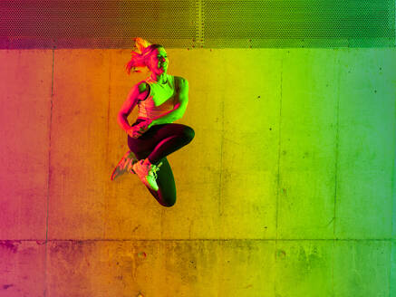 Aktive Frau, die in der Nähe einer neonfarbenen Wand waltet - STSF03777