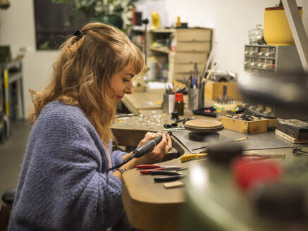 Happy goldsmith using work tool at workshop - LAF02818