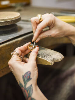 Hände eines Goldschmieds bei der Herstellung eines Rings mit Werkzeug in einer Werkstatt - LAF02819