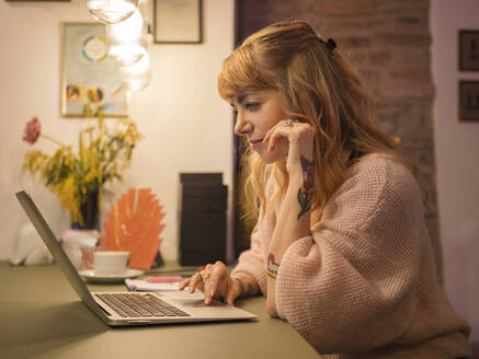 Freelancer wearing sweater using laptop at home - LAF02824