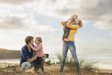 Glückliche Familie, die sich am Strand umarmt - SBOF04005