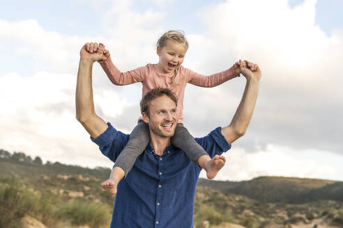 Happy father carrying daughter under cloudy sky - SBOF04009