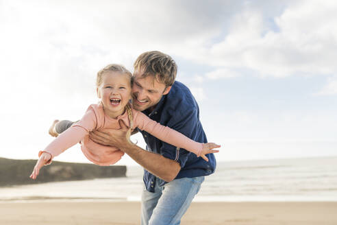 Glücklicher Vater spielt mit Tochter am Strand - SBOF04012