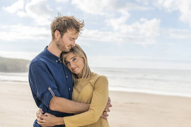 Happy man hugging woman at beach - SBOF04018