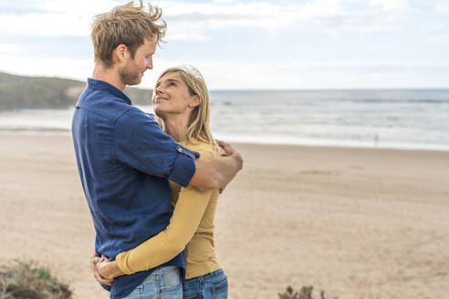 Lächelnde Frau und Mann schauen sich vor dem Meer an - SBOF04022