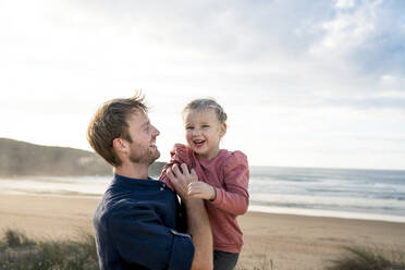 Happy father and daughter in front of sea on sunny day - SBOF04028