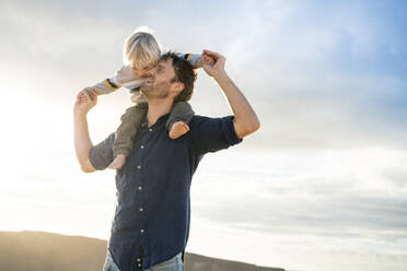 Happy father embracing son at beach - SBOF04035