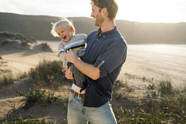 Fröhlicher Vater und Sohn genießen einen sonnigen Tag am Strand - SBOF04038