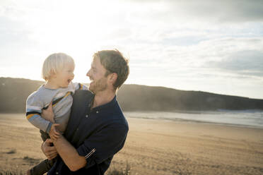 Cheerful father and son at beach on sunny day - SBOF04039