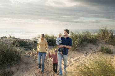 Happy parents walking with children under cloudy sky - SBOF04042