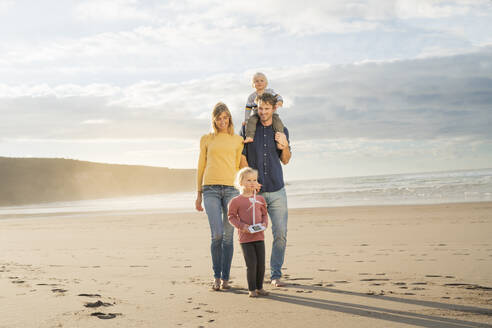 Glücklicher Vater und Mutter, die mit Kindern an einem sonnigen Tag vor dem Meer spazieren gehen - SBOF04045