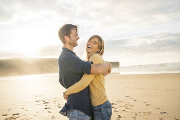 Glückliches Paar, das sich umarmt und seinen Urlaub am Strand genießt - SBOF04059