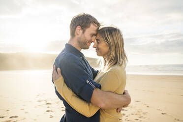 Lächelnder Mann und lächelnde Frau umarmen sich am Strand - SBOF04063