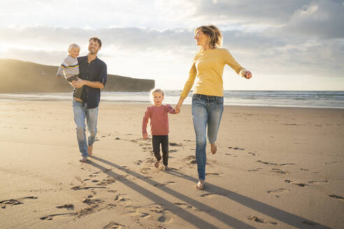 Smiling father and mother having fun with children at beach - SBOF04079