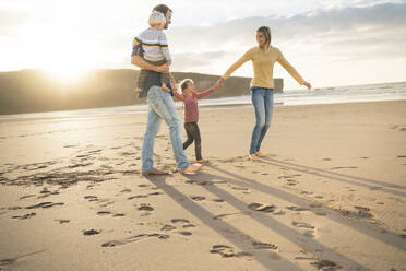 Lächelnde Mutter und Vater mit Kindern am Strand an einem sonnigen Tag - SBOF04080