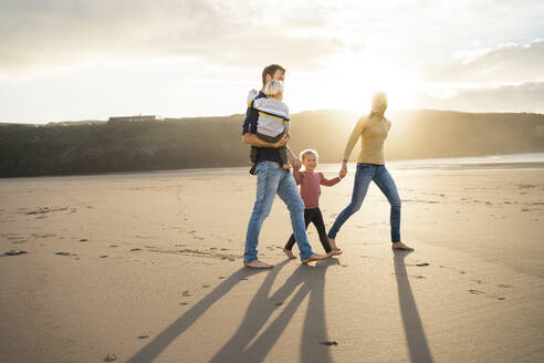 Vater und Mutter spazieren mit Kindern an einem sonnigen Tag am Strand - SBOF04082