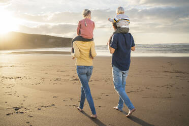 Mutter und Vater tragen Kinder auf den Schultern am Strand - SBOF04086