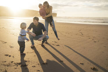 Smiling man and woman playing with children at beach - SBOF04095