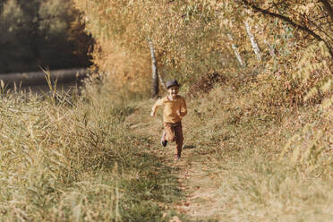 Cheerful boy running amidst plants - OSF02082