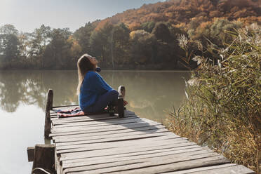 Woman sitting on jetty near lake - OSF02083