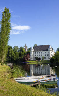 Austria, Upper Austria, Sankt Peter am Hart, Rowboat on bank of Mattig river with Hagenau Castle in background - WWF06283