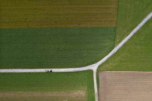 Österreich, Oberösterreich, Drohnenaufnahme eines Traktors auf einer Landstraße zwischen Feldern - WWF06296