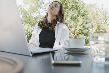 Businesswoman taking nap at table in garden - OSF02100